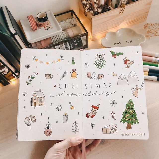 someone is holding up a christmas planner in front of their desk with other items on it