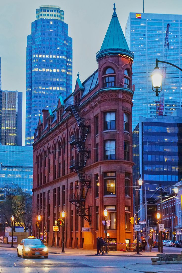 an old red brick building in the middle of a city with tall buildings behind it