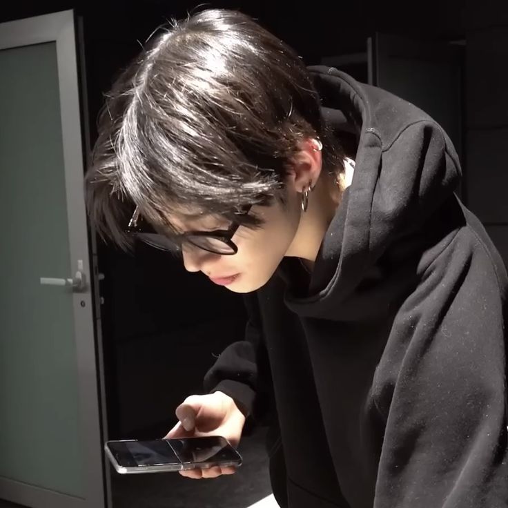 a person wearing glasses looking at a cell phone