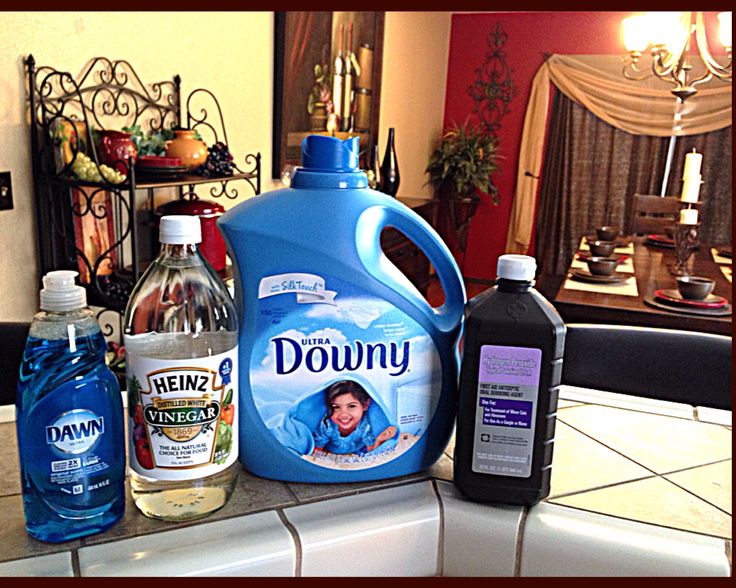 bottles of downy are sitting on the kitchen counter next to other household cleaning products