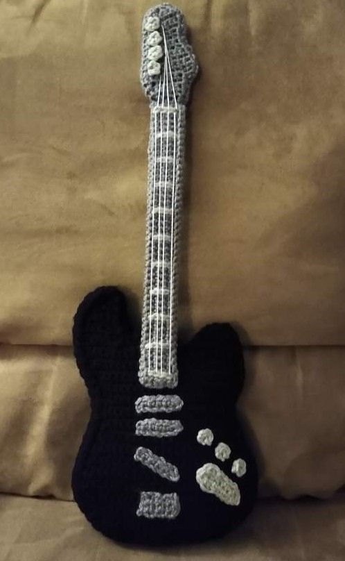 a stuffed animal with a guitar shaped like it's head on a sofa pillow