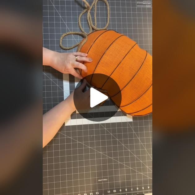 someone is making a pumpkin out of paper and yarn on a cutting board with scissors