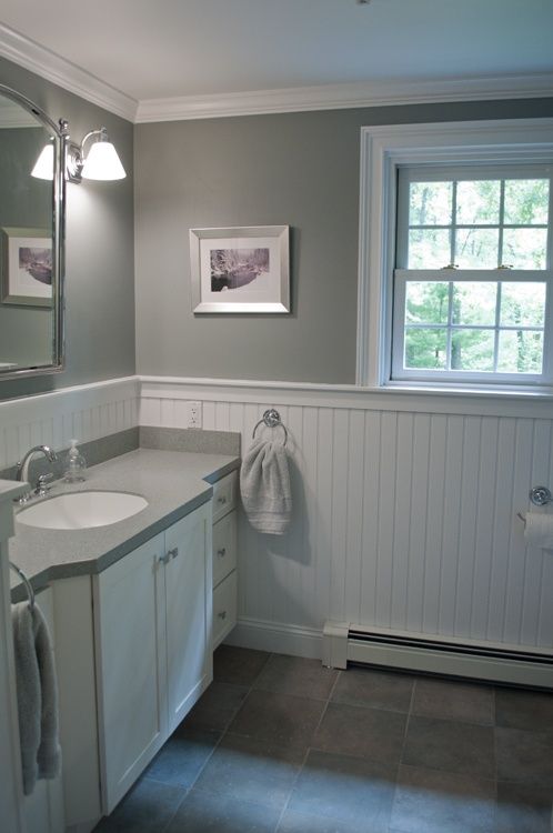 a bathroom with gray walls and white cabinets