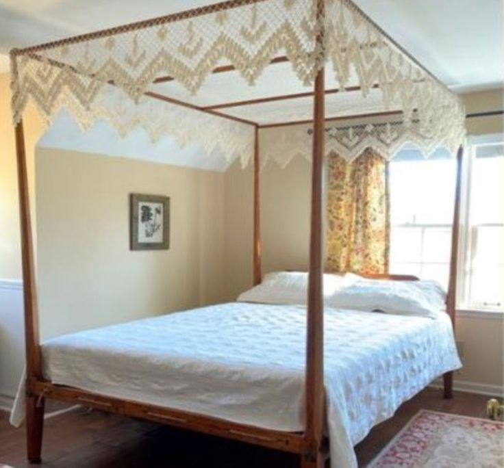 a white bed sitting in a bedroom on top of a hard wood floor next to a window