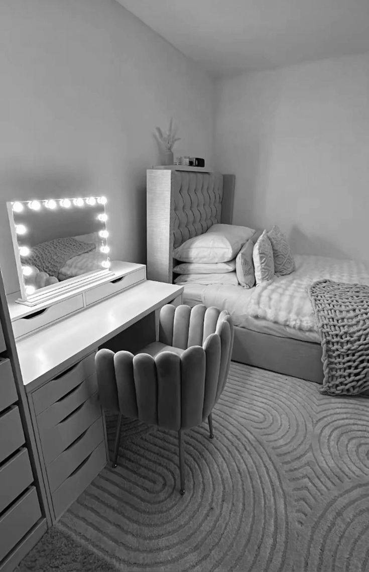 black and white photograph of a bedroom with a bed, dresser, mirror and chair