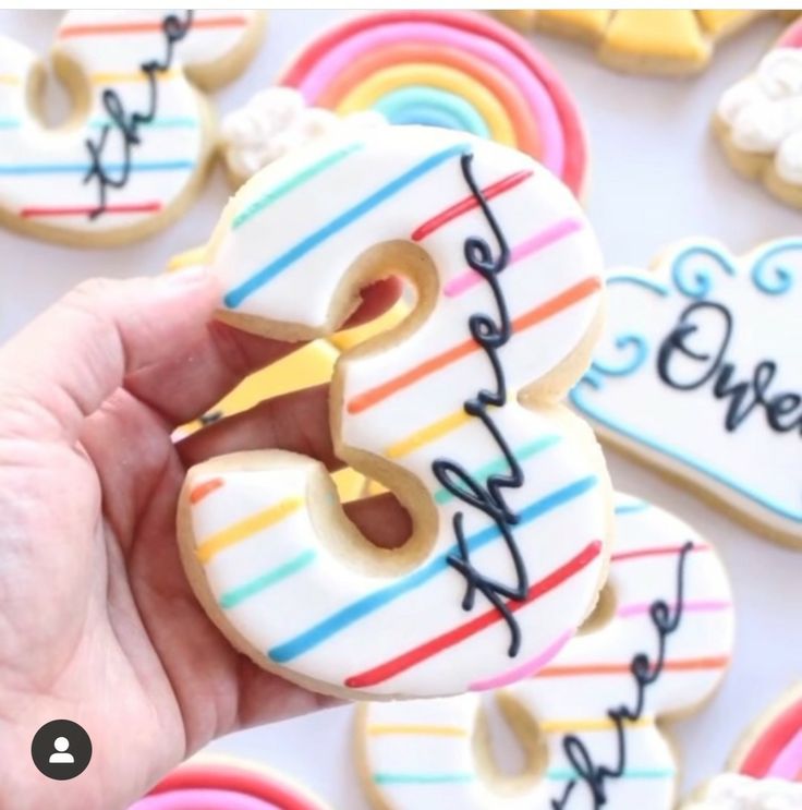 a person is holding some decorated cookies with the number 3 on them and rainbow stripes