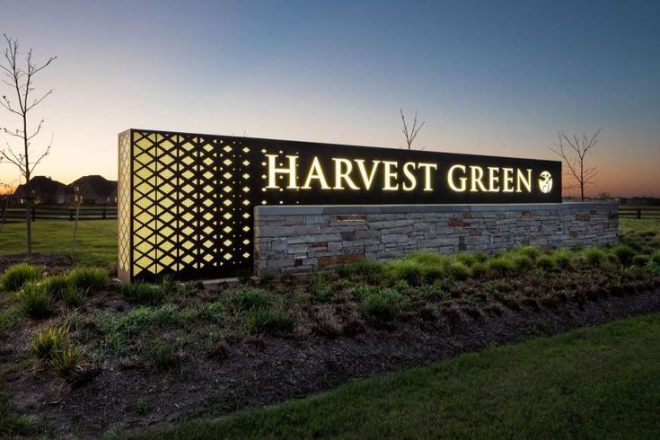 the sign for harvest green is lit up at night in front of an open field