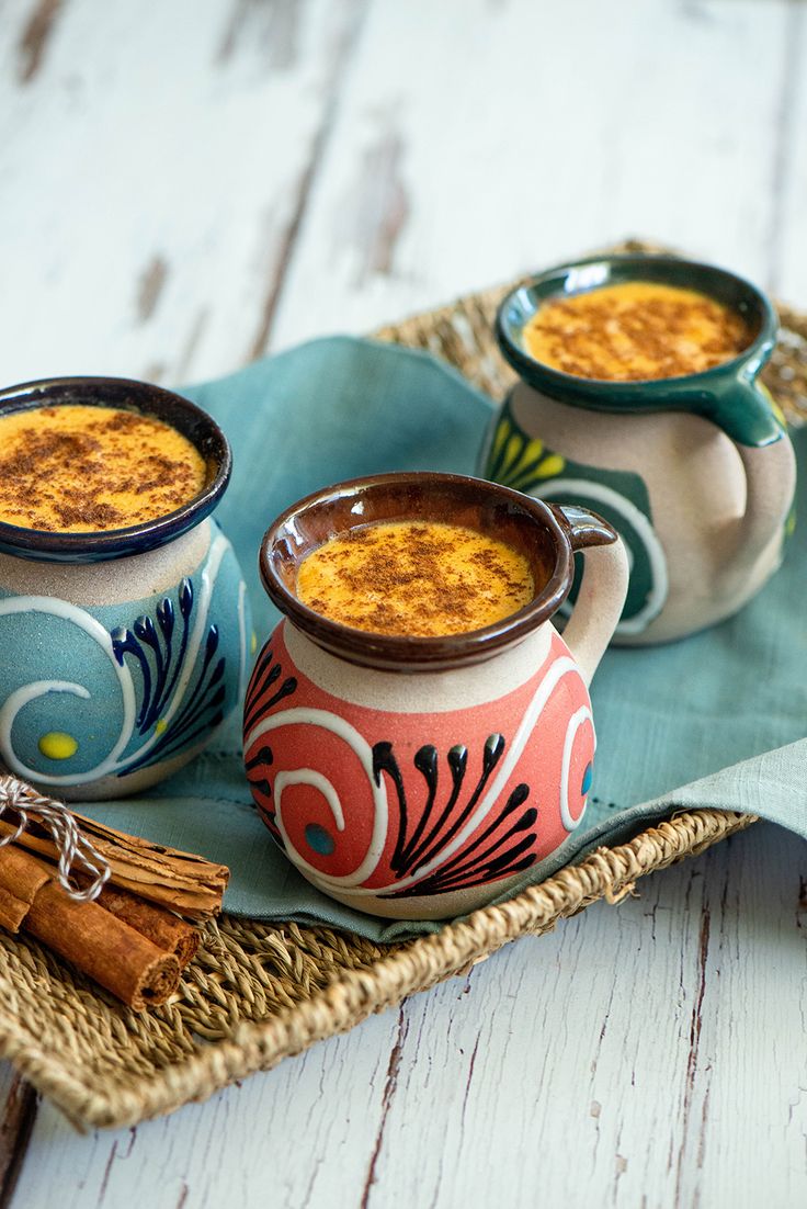 two mugs filled with food sitting on top of a blue and white tray next to cinnamon sticks