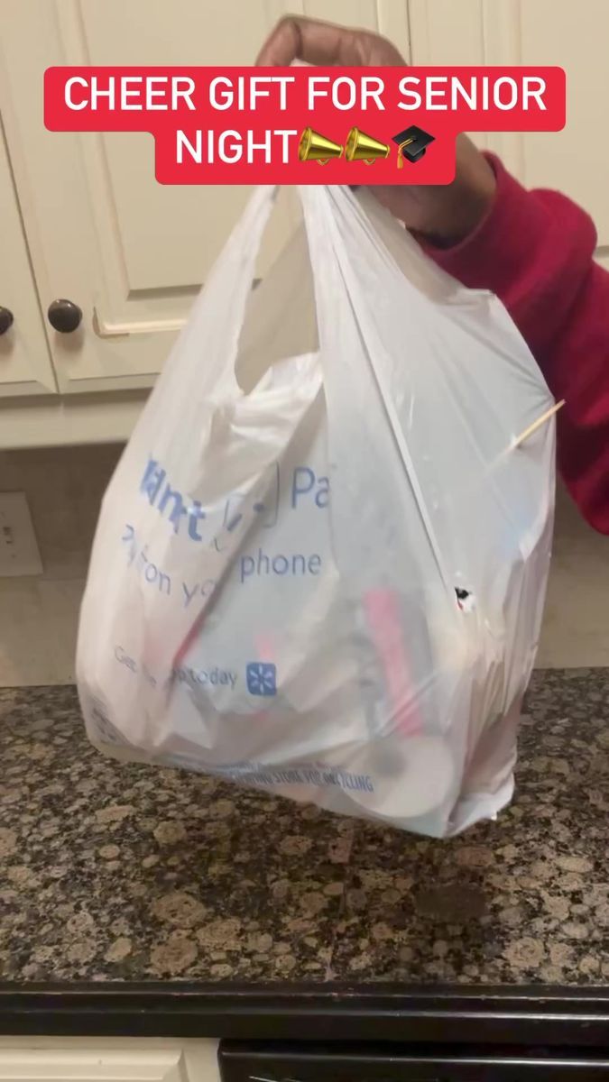 a person holding a plastic bag with the words cheer gift for senior night on it