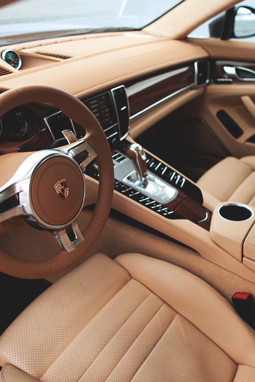 the interior of a luxury car with beige leather and wood trims, steering wheel and center console