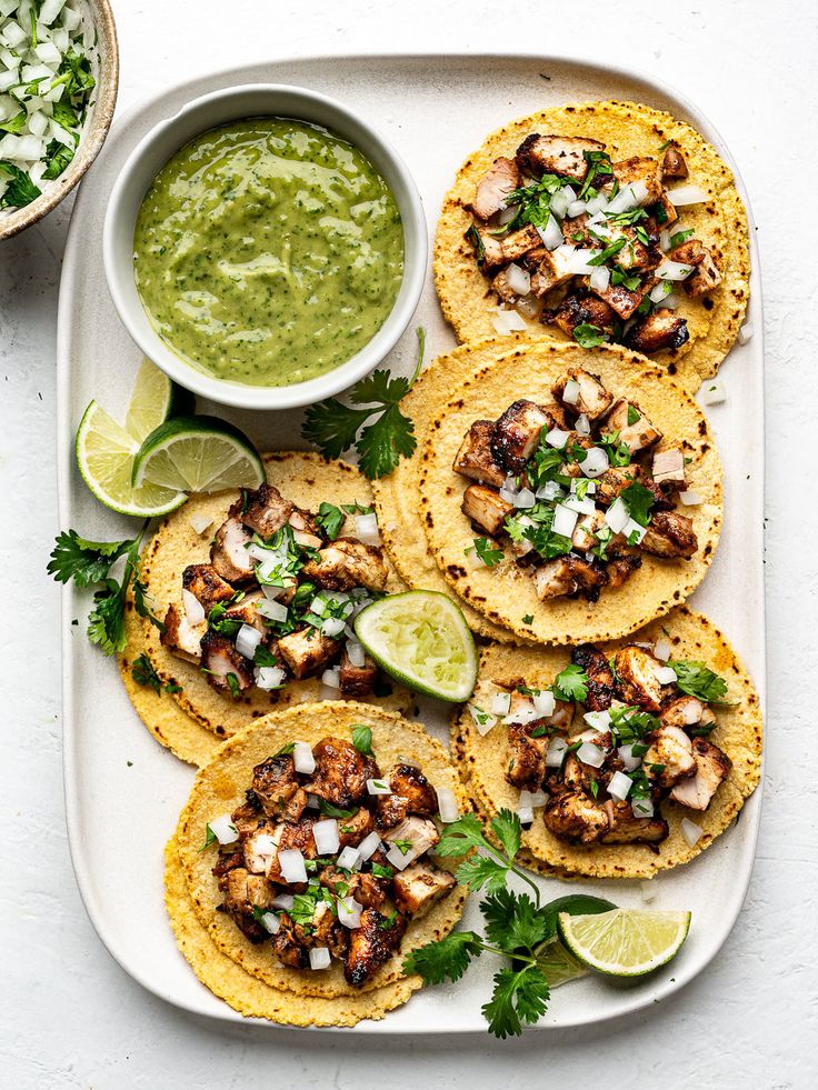 chicken tacos with guacamole and cilantro sauce on a platter