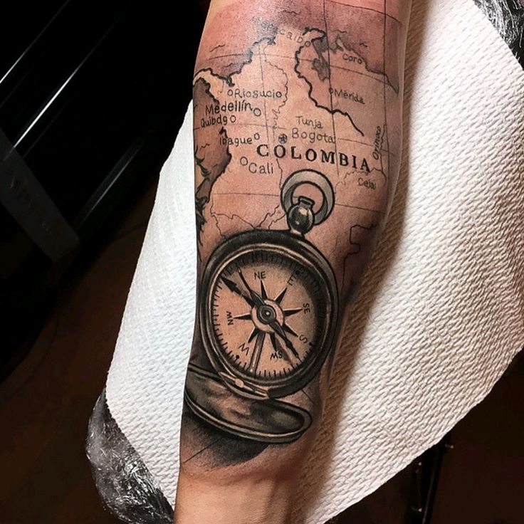 a man with a tattoo on his arm has a map and a compass in it