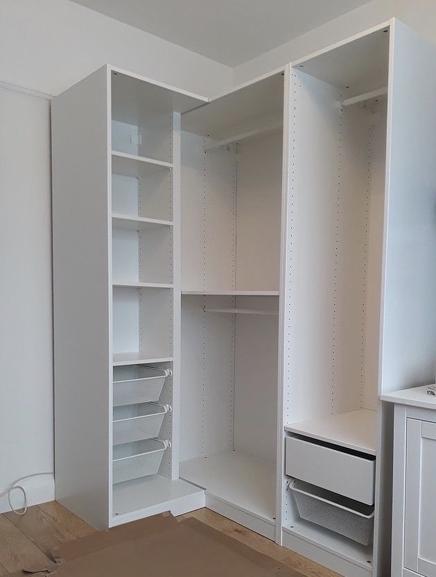 an empty closet with white shelves and drawers