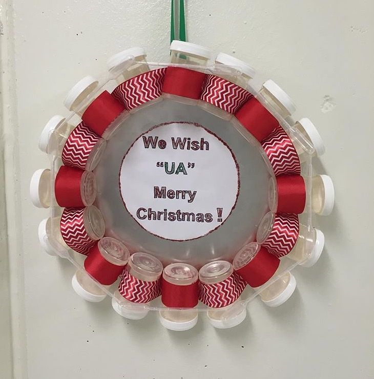 a christmas wreath hanging on the wall with red and white spools attached to it