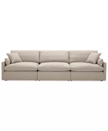 a beige couch with pillows on the top and bottom, in front of a white background