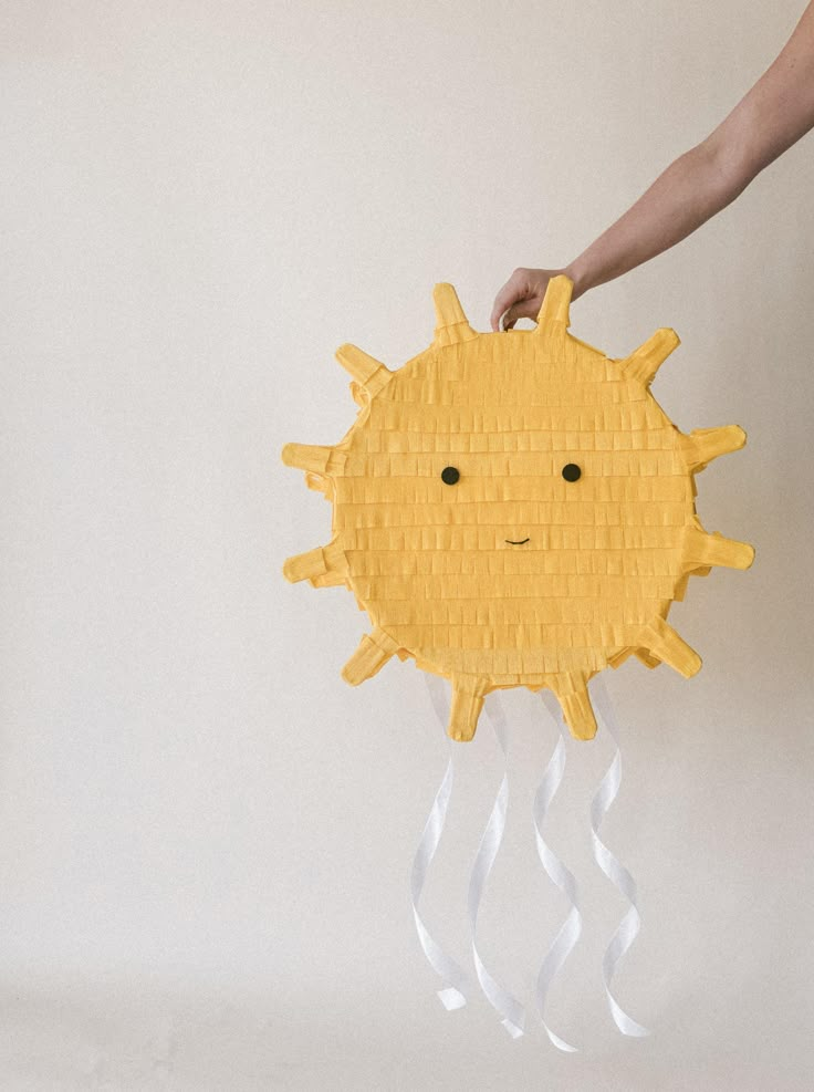 a person holding a paper plate with a yellow sun on it's face and hands