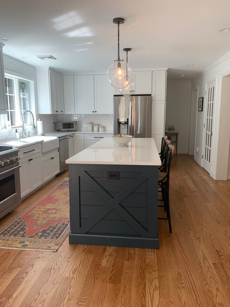 a large kitchen with an island in the middle of it and white cabinets on both sides