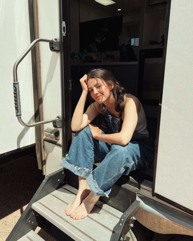 a woman sitting on the steps of a truck