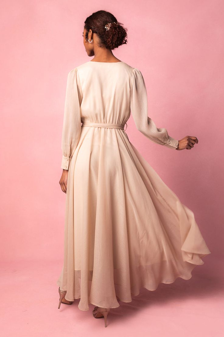 Introducing the Andie Dress in Champagne. Aka the perfect blend of style and comfort. This maxi dress features a soft champagne base with a flattering faux wrap bodice and elastic waist for a perfect fit. The functional pockets and lined bodice and skirt add practicality, while the fabric's stretch makes it suitable for both maternity and nursing. With a v neckline and long, unlined sleeves, this dress is versatile AND chic. Fitted V-neck Maxi Dress With Elastic Waistband, Elegant V-neck Midi Dress With Elastic Waistband, Feminine Formal Maxi Dress, Modest V-neck Dress With Elastic Waistband, Fitted Waist Maxi Dress For Daywear, Feminine Pleated Waist Maxi Dress For Spring, Formal Fitted Maxi Dress With Gathered Waist, Beige Ruched V-neck Maxi Dress, Maxi Length Ruched Midi Dress For Bridesmaids