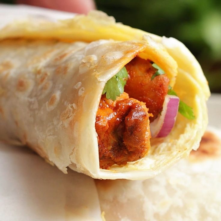 a burrito filled with meat and veggies sitting on top of a white plate