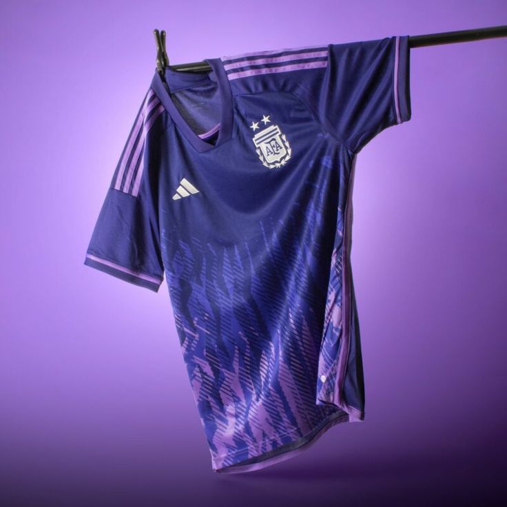 an adidas jersey hangs on a clothesline against a purple background in this image