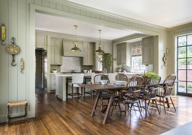 a dining room table and chairs in front of an open kitchen with wood flooring