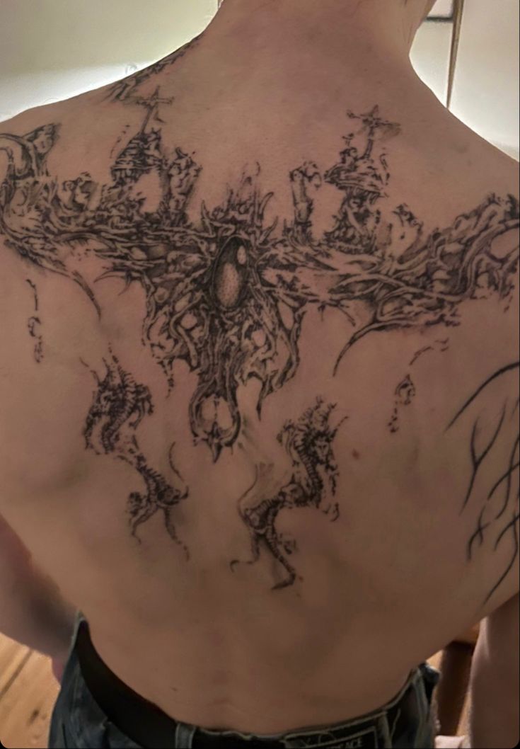 the back of a man with tattoos on his chest