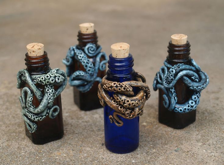 three blue bottles with snakes wrapped around them sitting on the ground next to each other