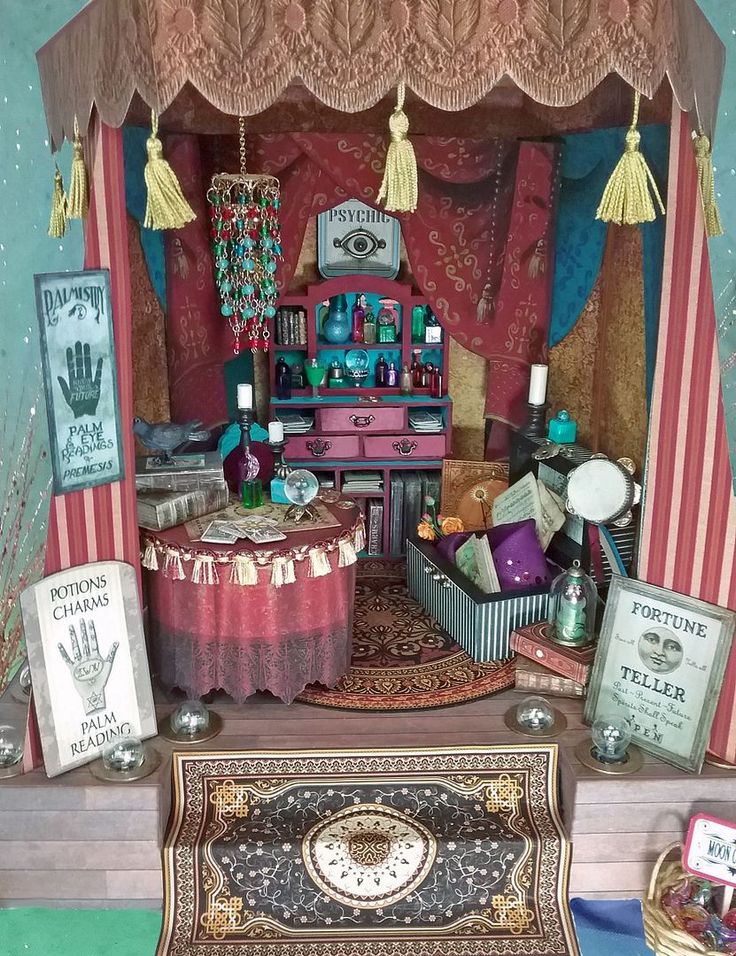 a doll house with furniture and accessories on the floor in front of a red curtain