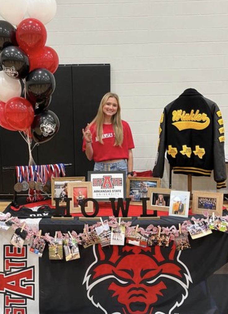 a woman standing in front of a table with pictures and balloons