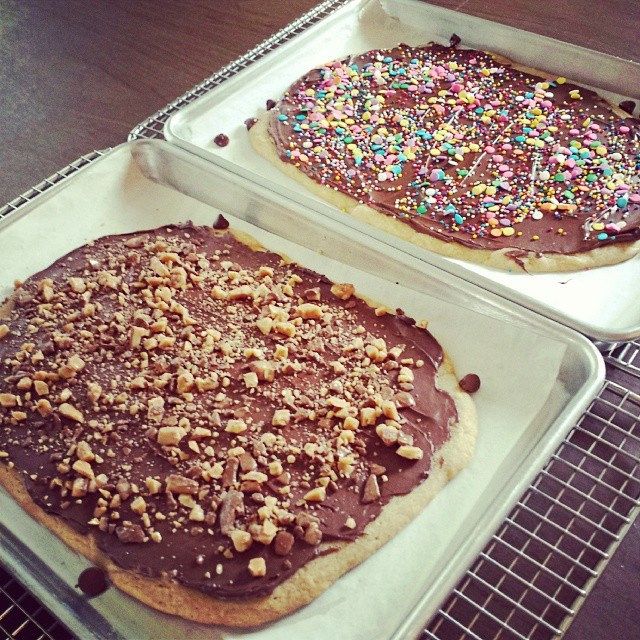 two pans filled with chocolate and sprinkle covered cookies on top of a table