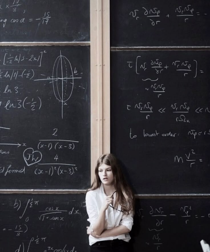 a young woman standing in front of a blackboard