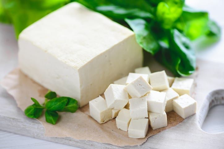 cubes of tofu and greens on a cutting board