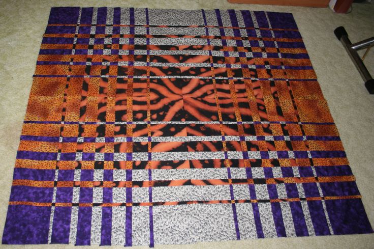 an orange and purple quilt on the floor