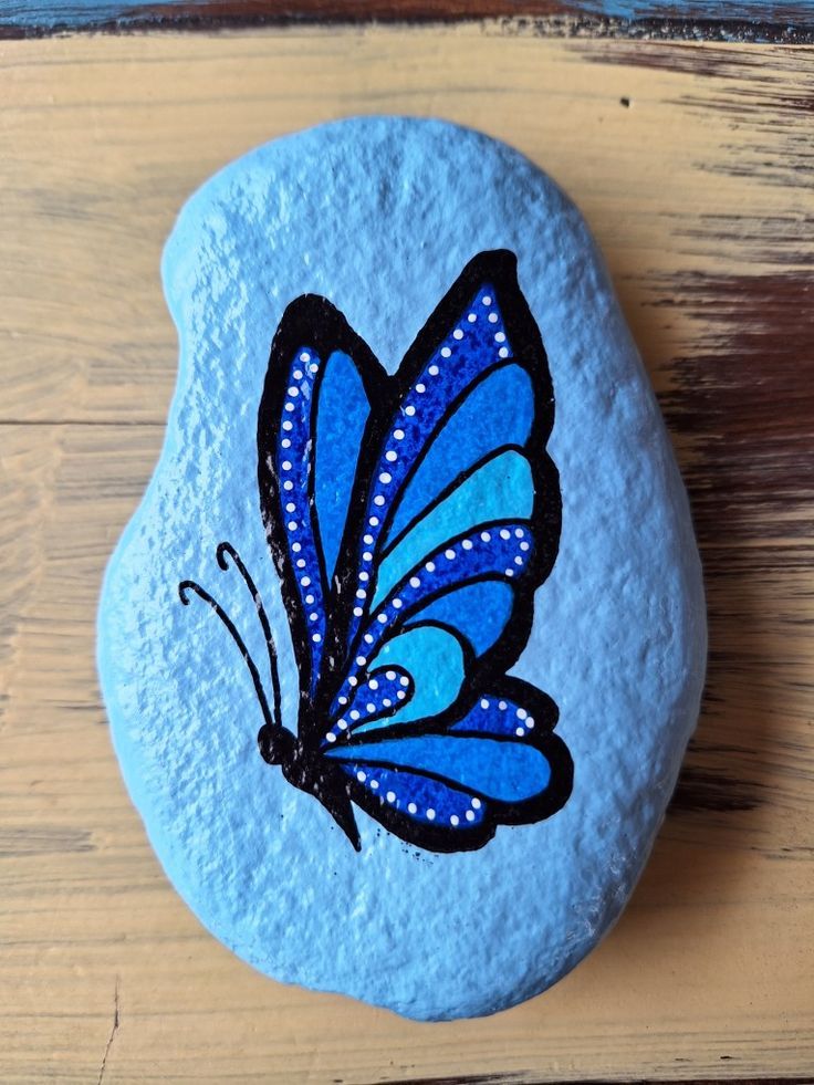 a painted rock with a blue butterfly on it