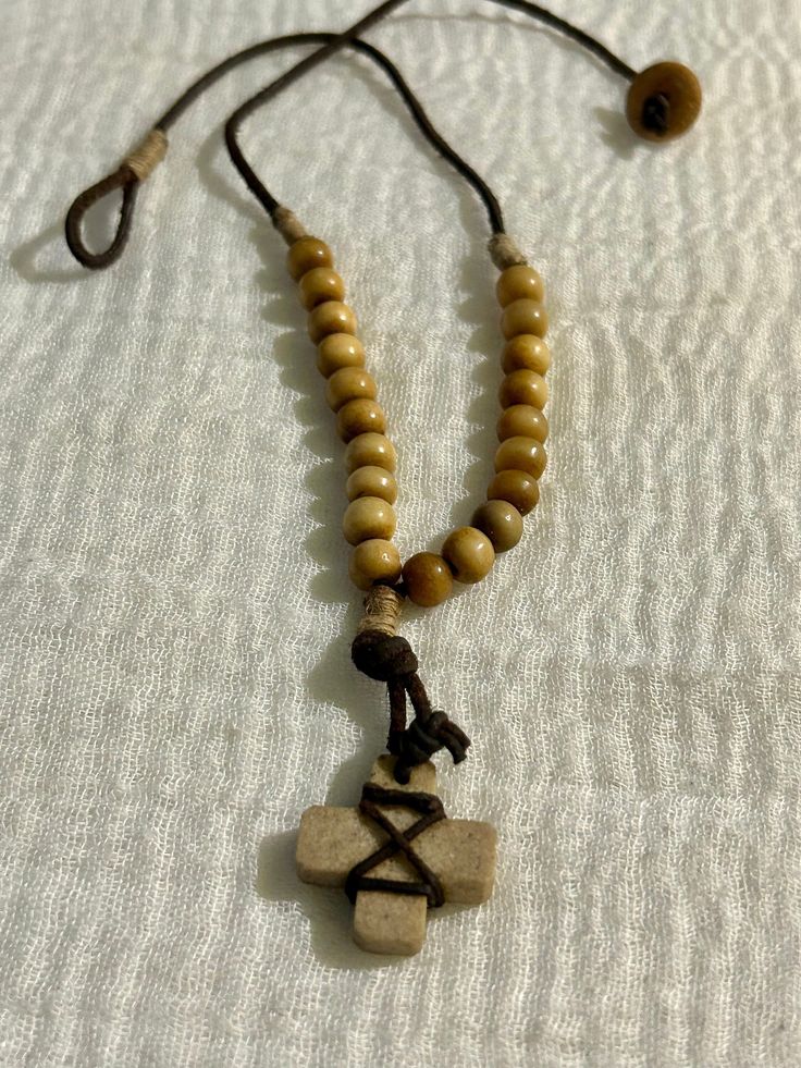 Add a unique touch to your wardrobe with this vintage tribal cord necklace. The brown beaded design features a charming stone cross pendant, making it a perfect accessory for any occasion. With a necklace length of 18 inches and a button closure, it is suitable for both men and women. The necklace has a beaded style and a pendant/locket type of charm, adding a touch of elegance to your outfit. The chain type is cord, and the country of origin and manufacture are unknown. The necklace is ideal for those who appreciate ethnic, regional, and tribal jewelry. Spiritual Beaded Cross Pendant Necklace, Bohemian Cross Beaded Necklace Gift, Adjustable Cross Pendant Jewelry, Bohemian Cross-shaped Beaded Necklaces, Adjustable Vintage Cross Pendant Necklace, Vintage Adjustable Cross Pendant Necklace, Bohemian Beaded Cross Necklace, Casual Brown Necklace With Adjustable Cord, Adjustable Cross Necklace For Festivals