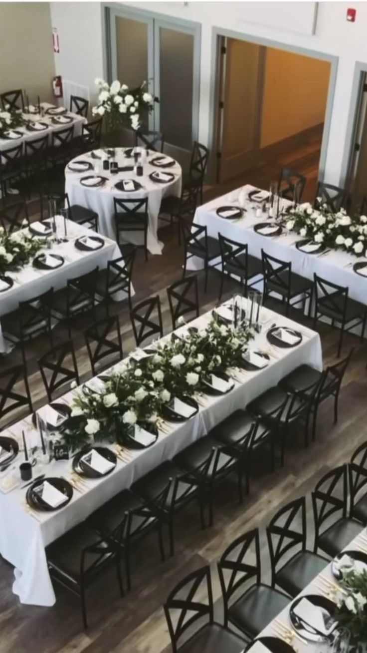 tables set up with white and black tablecloths for an event or function in a large room