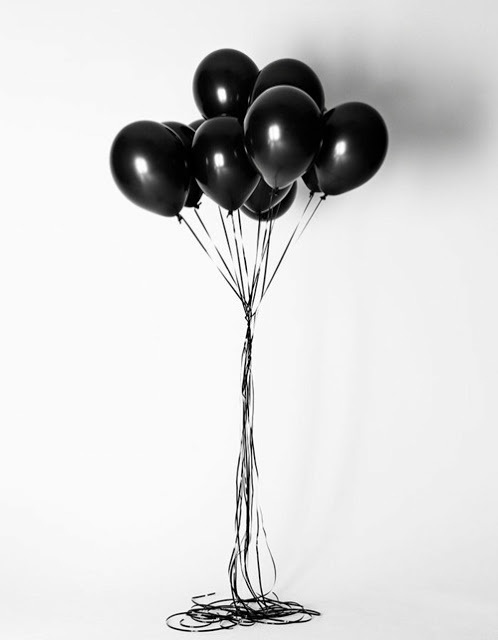 a bunch of black balloons floating in the air on a white background with streamers