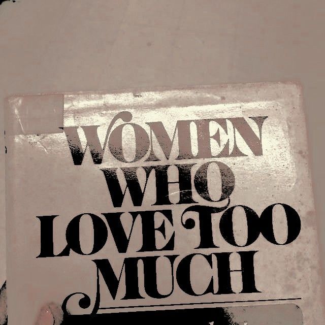 a woman who loves too much is holding up a sign that says, women who love too much