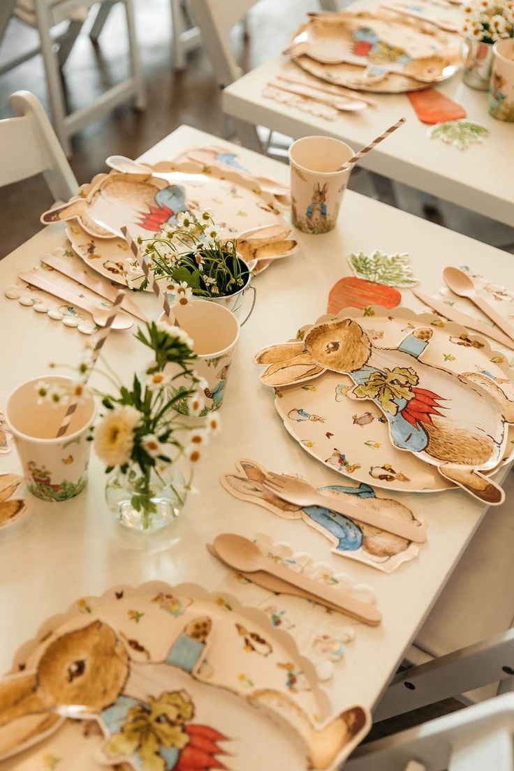 the table is set with plates, cups and utensils for children to eat