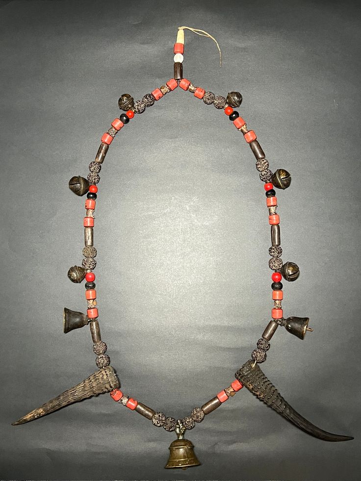 This Interesting and beautiful Old Primitive Shaman Metal Chain holy spiritual Necklace is from Western Nepal (Jumla) with: - Bronze Bells - Old Red Glass Beads - Rudraksha Beads - Seashell Beads - Cylindrical Metal Beads - Snake Bone - Wild Mountain Goat Horns - Beautiful Bronze Bell Centerpiece Shamans would wear necklaces like these when performing rituals or ceremonies. Collector and museum quality piece. Measurements: Length - 27 inches Weight - 704 grams * Colors may vary slightly in perso Shaman Necklace Bones, Traditional Jewelry With Wooden Beads For Blessing, Spiritual Large Beads Necklace For Rituals, Spiritual Jewelry For Traditional Ceremonies And Festivals, Spiritual Necklaces With Large Beads For Rituals, Traditional Hand-strung Necklaces For Blessing, Traditional Beaded Jewelry For Blessing, Traditional Hand-strung Necklace For Ceremonial Occasions, Bell Centerpiece