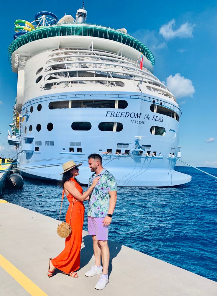 a man and woman standing next to each other in front of a cruise ship