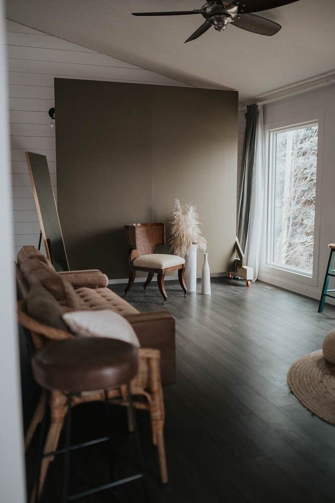 a living room filled with furniture next to a large window and a wooden floor covered in rugs