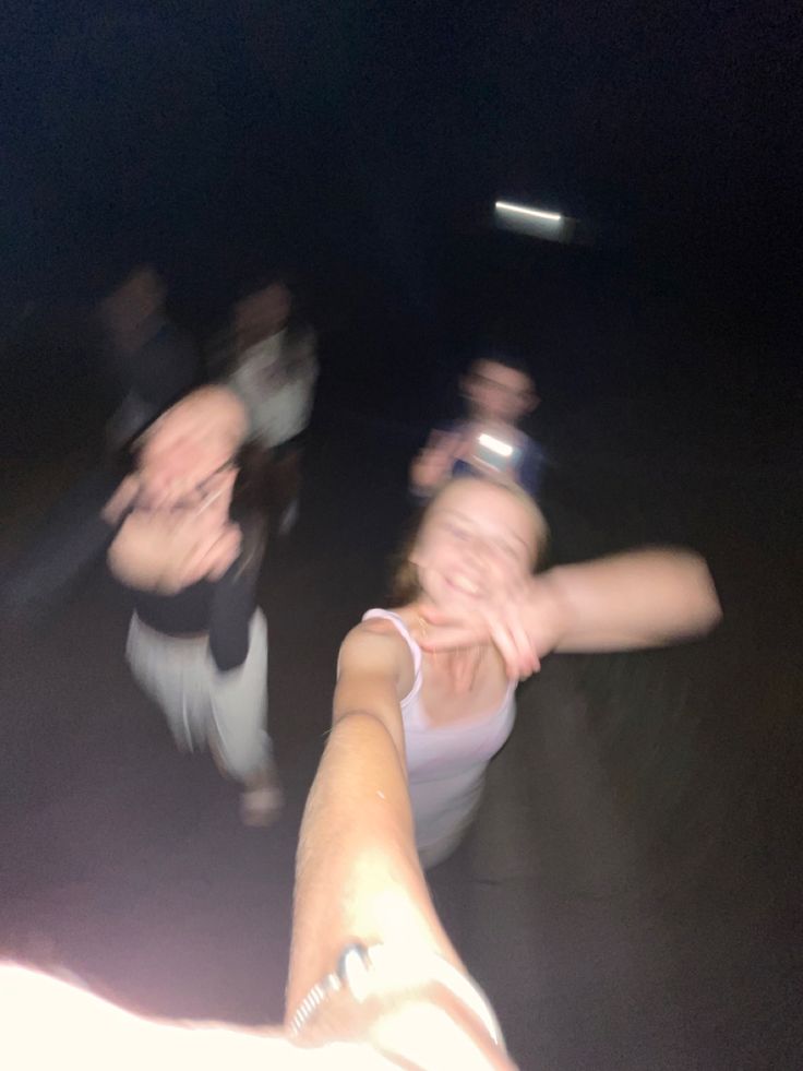 three people are dancing in the dark with their hands together and one person is holding out her hand