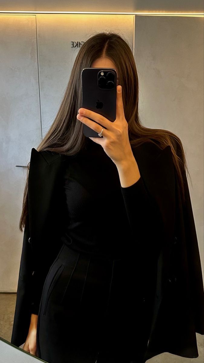 a woman taking a selfie in front of a mirror with her cell phone up to her ear