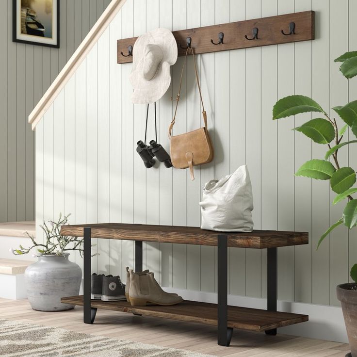 a wooden bench sitting next to a plant in a living room under a stair case