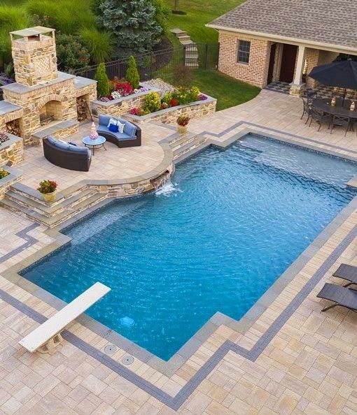 a backyard with a pool, fire place and patio furniture in the middle of it