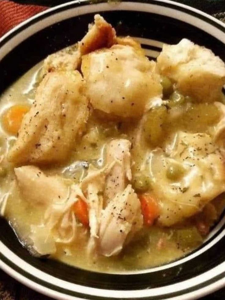 a bowl filled with chicken and dumplings on top of a table