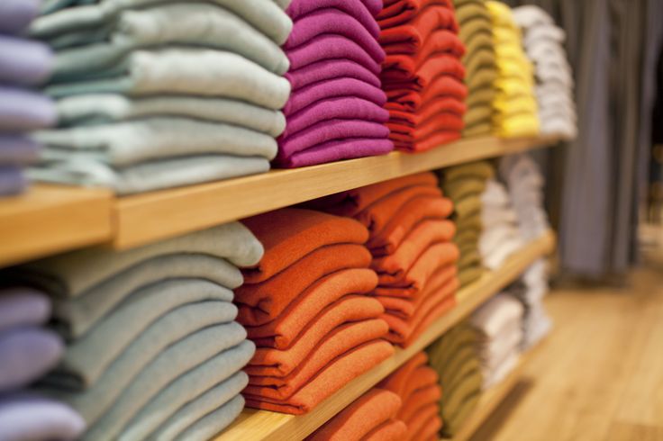 rows of folded shirts on shelves in a store