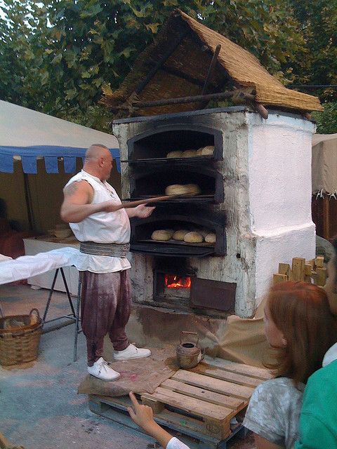 a man standing in front of an outdoor oven